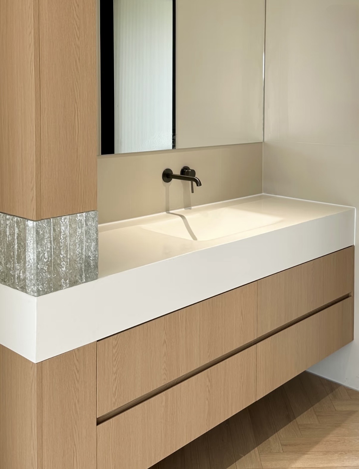 Lave bespoke oak vanity with integrated sintered stone basin, full-height oak column and herringbone floor — Minimal Japandi installation