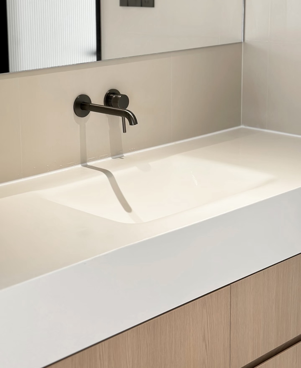 Close-up of Lave integrated sintered stone basin with wall-mounted matte black tap — stone and wood Japandi material pairing