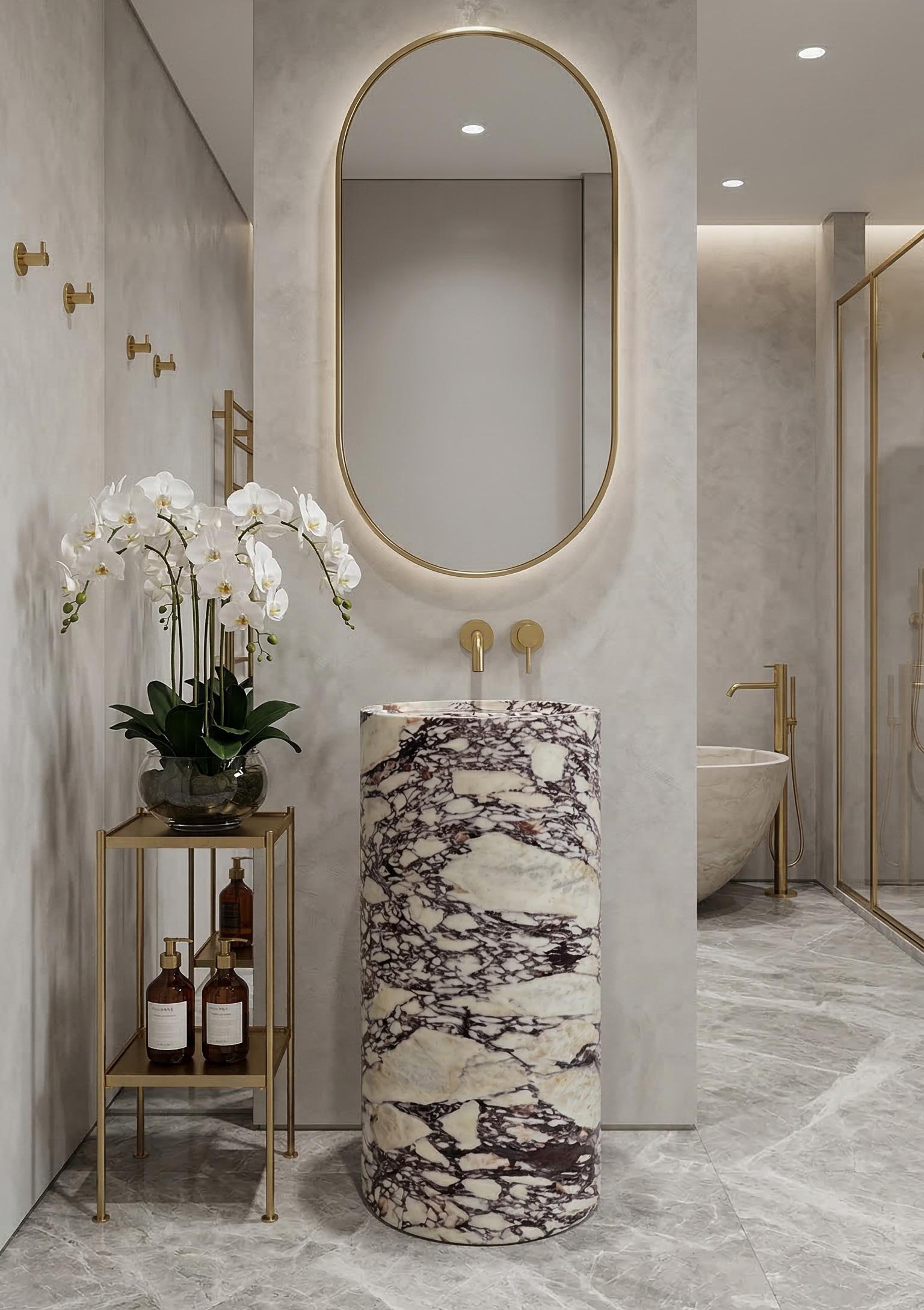 Calacatta Viola marble column pedestal sink with brushed gold oval mirror and matching freestanding bath in background